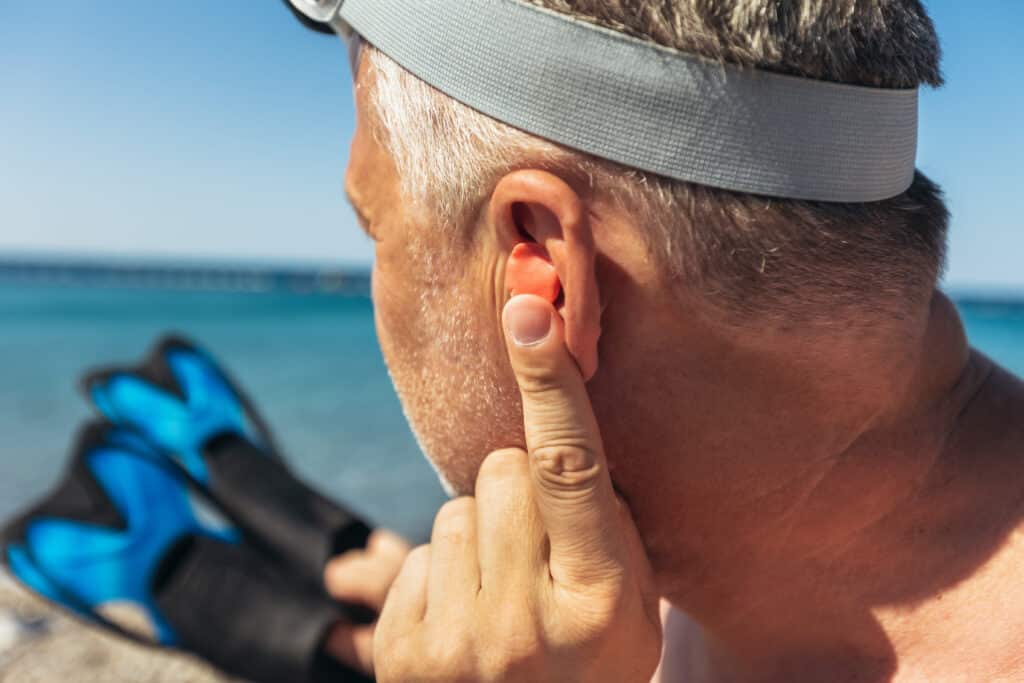 Man wearing swimming ear plugs before swimming