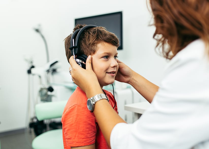 Kid with hearing loss getting a hearing evaluation by an audiologist